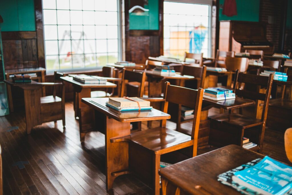 An empty vintage classroom with wooden desks and books on each desk, reflecting a classic educational setup at a lower academy